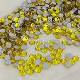 Citrine yellow round crystal rhinestones with flat backs, scattered pile of gems