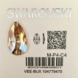 A faceted teardrop-shaped Swarovski crystal rhinestone in a Crystal Golden Shadow, displayed on its original light beige backing card with the brand name 'SWAROVSKI' in silver glitter text, product code 'M-P4-C4', a barcode, and a QR code.