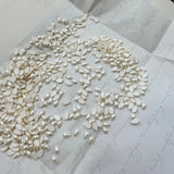 Pear-shaped pearl-effect hotfix crystals, cream/white, scattered on backing sheet