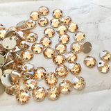 real photo of a group of Swarovski round sew on flat back elements in Golden Shadow colour